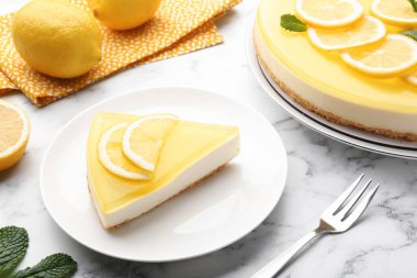 Lezzetli limonlu cheesecake, çatal, nane ve narenciye meyveleri beyaz mermer masada, yakın plan.