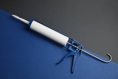 Renkli arka planda bir tutkal tabancası, üst görünüm