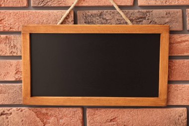Tuğla duvarda boş küçük bir tahta.