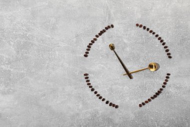 Kahve çekirdekleri ve kaşıklar gri masada saati temsil ediyor. Metin için boşluk