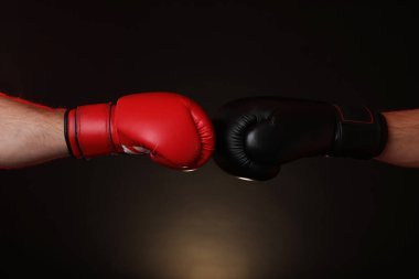 Boks eldivenli adamlar karanlık arka planda dövüşüyor, yakın plan.