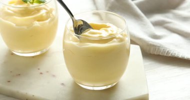 Beyaz ahşap masada nefis vanilyalı puding yiyen bir kadın.