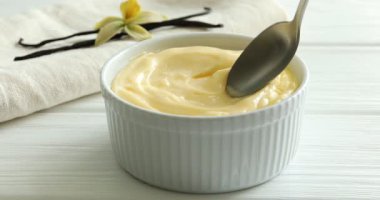 Beyaz ahşap masada nefis vanilyalı puding yiyen bir kadın.