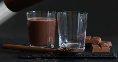 Siyah masada bardağa çikolatalı süt dökmek, yakın plan.