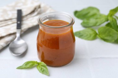 Cam kavanozda lezzetli köri sosu ve beyaz fayanslı masada fesleğen, yakın plan.