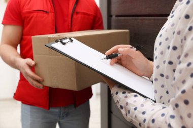 Kutulu ve alıcısı olan kurye paket teslimatı için imza veriyor, kapalı.