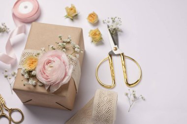 Çiçekçi. Beyaz arkaplanda kutu, çiçek, makas ve kurdele, yakın plan