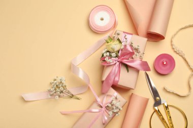 Çiçekçi. Kutular, çiçekler, kurdele, yanan mum ve makas bej arka planda, düz yerde. Metin için boşluk