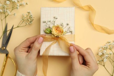 Çiçek kutusu, çiçek, makas ve bej arka planda kurdele olan bir çiçekçi.