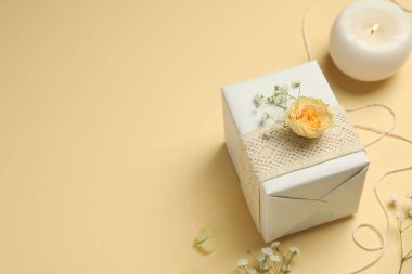 Çiçekçi. Kutu, çiçekler ve yanan mum bej arka planda, metin için boşluk