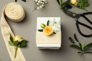 Çiçekçi. Kutu, çiçekler, yapraklar ve makas gri arka planda, düz yatar
