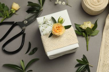 Çiçekçi. Kutu, çiçekler, yapraklar ve makas gri arka planda, düz yatar