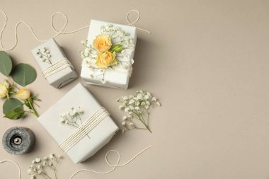 Çiçekçi. Kutular, çiçekler ve yanan mum açık gri arka planda, düz yerde. Metin için boşluk