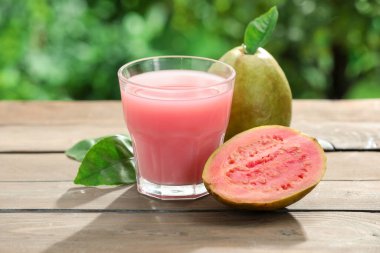 Guava suyunu tazeliyorum ve ahşap masada taze meyveler, yakın plan.