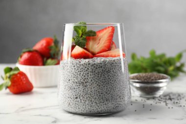 Çilekli lezzetli chia pudingi ve beyaz mermer masada nane şekeri. Yakın plan.