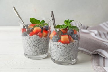 Çilekli Chia pudingi, yaban mersini ve beyaz tahta masada bardakta nane şekeri.