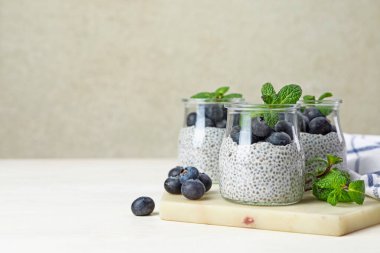 Yaban mersinli lezzetli chia pudingi ve nane şekeri ışıklı masada, metin için yer var.