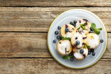 Yaban mersinli lezzetli çörekler, pudra şekeri ve ahşap masa üzerinde nane şekeri, üst manzara. Metin için boşluk