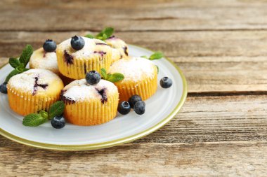 Yaban mersinli lezzetli kekler, pudra şekeri ve ahşap masada nane şekeri, yakın plan. Metin için boşluk