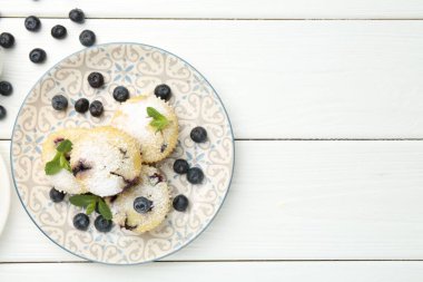 Yaban mersinli lezzetli çörekler, pudra şekeri ve beyaz ahşap masada nane şekeri, düz yatak. Metin için boşluk
