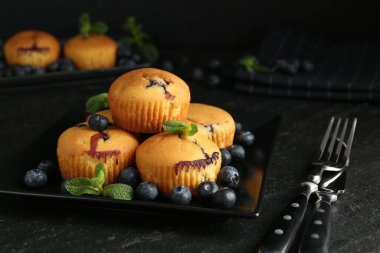 Yaban mersinli lezzetli kekler, nane ve çatal bıçak seti koyu dokulu masa, yakın plan.