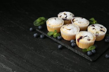 Yaban mersinli lezzetli çörekler, pudra şekeri ve koyu dokulu masada nane şekeri. Metin için boşluk