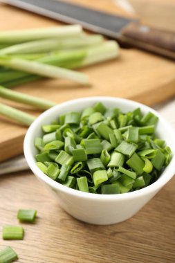 Taze yeşil soğanları kâsede, bıçağı da ahşap masada yakın planda kes.