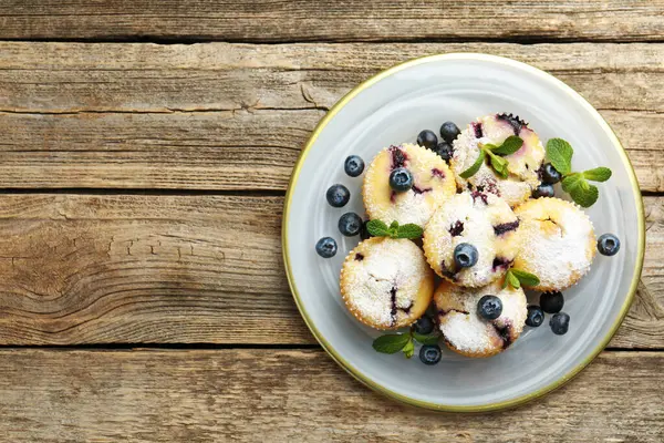 Yaban mersinli lezzetli çörekler, pudra şekeri ve ahşap masa üzerinde nane şekeri, üst manzara. Metin için boşluk