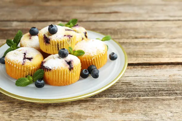 Yaban mersinli lezzetli kekler, pudra şekeri ve ahşap masada nane şekeri, yakın plan. Metin için boşluk