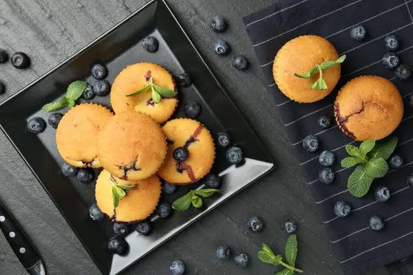 Yaban mersinli lezzetli çörekler ve koyu dokulu masa üzerinde nane şekeri.