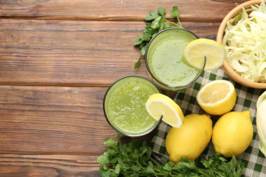 Sağlıklı maydanozlu bardaklar, limonlar ve lahanalar ahşap masada, düz uzanmış. Metin için boşluk