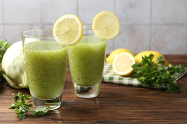 Sağlıklı maydanoz kadehleri, limonlar ve lahanalar ahşap masada, yakın plan.