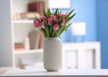 Beyaz masadaki vazoda duran bir buket güzel lale.