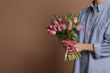 Koyu bej arka planda bir buket güzel lalesi olan kadın, yakın plan. Metin için boşluk