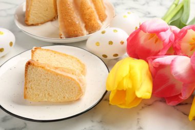 Lezzetli kek parçaları, Paskalya yumurtaları ve laleler açık mermer masada, yakın plan.