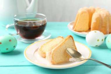 Lezzetli kek parçaları, paskalya yumurtası ve çay açık mavi ahşap masa, yakın plan.