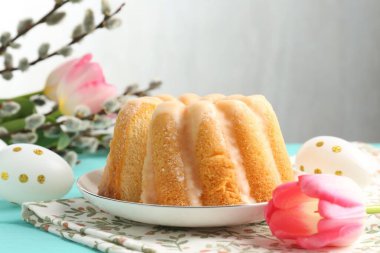 Lezzetli kek, Paskalya yumurtası, söğüt dalları ve açık mavi ahşap masada laleler.