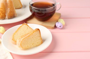 Lezzetli kek parçaları, pembe ahşap masada paskalya yumurtası ve çay, yakın plan.