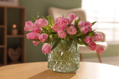 Güzel laleler vazoda, ahşap masada, yakın plan.