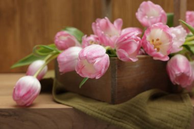 Güzel laleler sepetin içinde, ahşap masada, yakın plan.