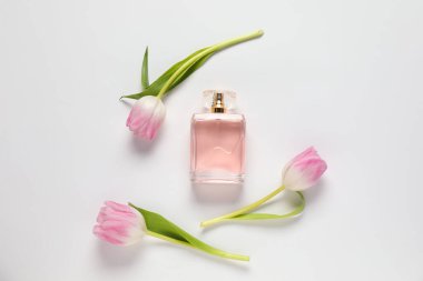 Bir şişe aromalı parfüm ve beyaz arka planda güzel laleler.