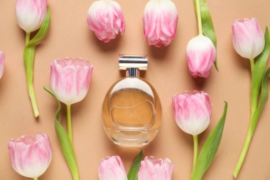 Düz kompozisyon, aromatik parfüm şişesi ve bej arka planda güzel laleler.