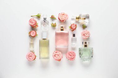 Düz kompozisyon, beyaz arka planda aromatik parfüm şişeleri ve güzel çiçekler vardı.