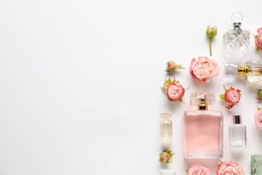 Düz kompozisyonda aromatik parfüm şişeleri ve beyaz arka planda güzel çiçekler vardı. Metin için boşluk