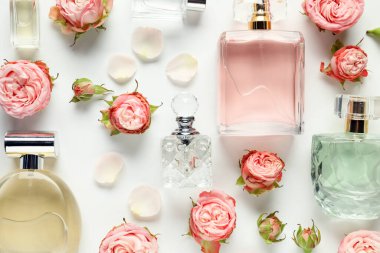 Düz kompozisyon, beyaz arka planda aromatik parfüm şişeleri ve güzel çiçekler vardı.