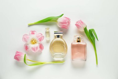 Düz kompozisyon, beyaz arka planda aromatik parfüm şişeleri ve güzel çiçekler vardı.