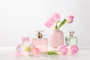 Aromatik parfüm şişesi ve beyaz masa üzerinde beyaz arka planda güzel laleler.