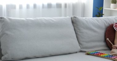 Evdeki kanepede oyuncak ksilofon çalan tatlı kız. Kamera sağa hareket ediyor