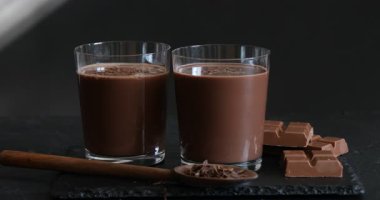 Siyah masada sütün üzerine çikolata parçacıkları serpiştirmek, yakın plan.