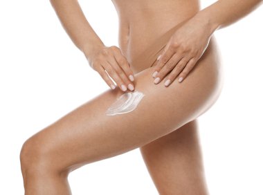 Beyaz arka plana anti-selülit kremi süren kadın, yakın plan.